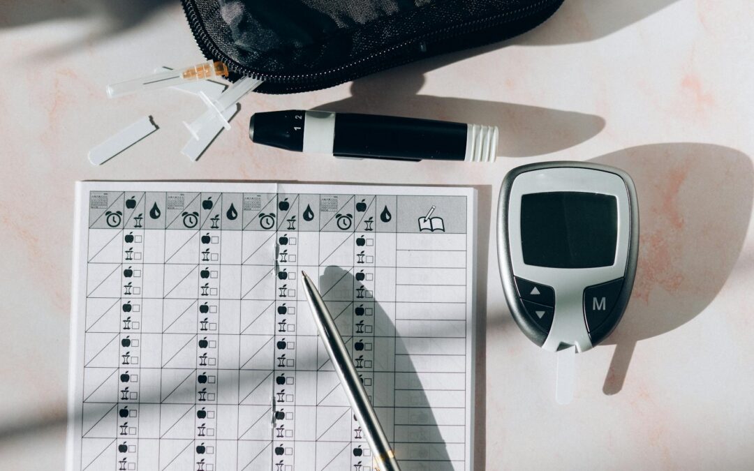 Close-up of a diabetes monitoring kit with glucometer, pen, and test strips on a table.
