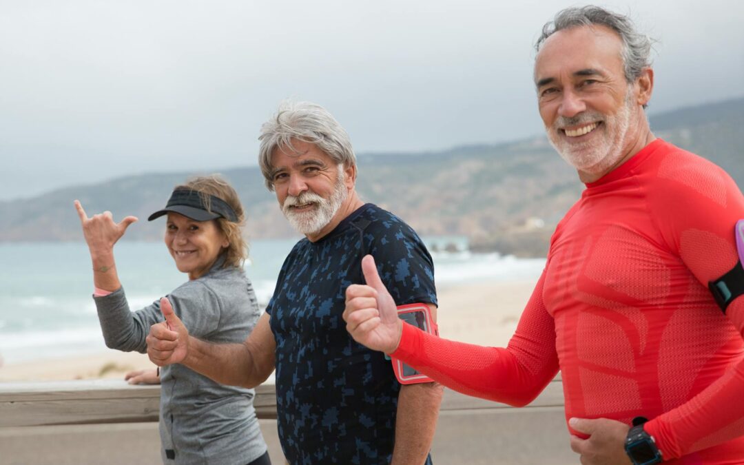 Smiling senior friends exercising on a beach in Portugal, embracing a healthy lifestyle.