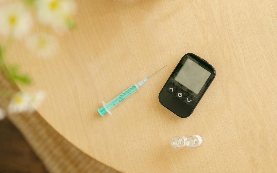 Close-up of a glucometer, syringe, and vials on a wooden table for diabetes care.
