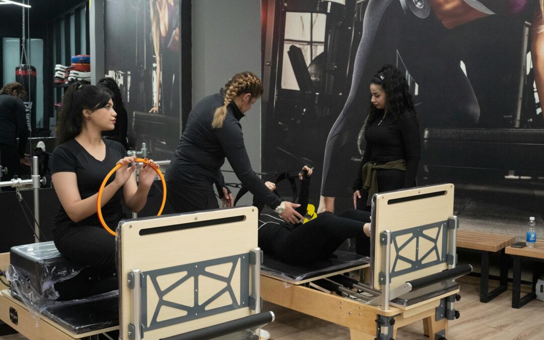 Three women engaging in Pilates exercise with equipment inside a gym studio.