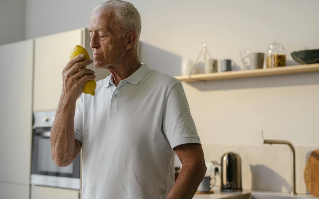 Elderly man in kitchen savoring the fresh scent of a lemon, highlighting tranquility.