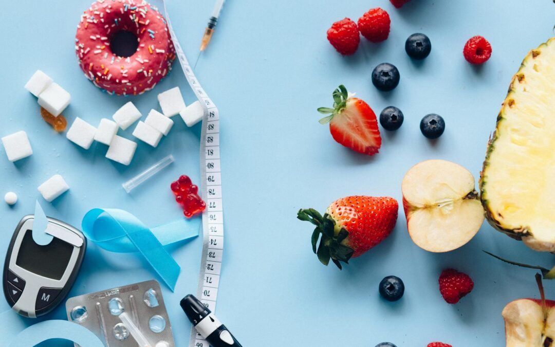 Flatlay of fruits, sugary treats, and diabetes tools on a blue background, symbolizing health choices.