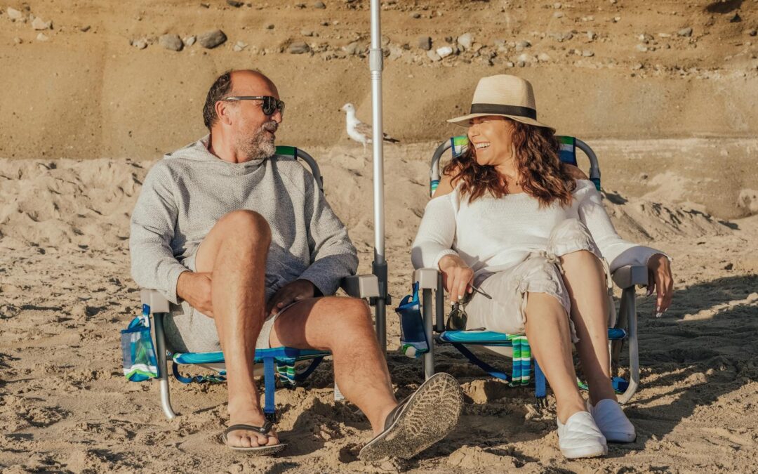 Happy senior couple seated on the beach enjoying a sunny day together.